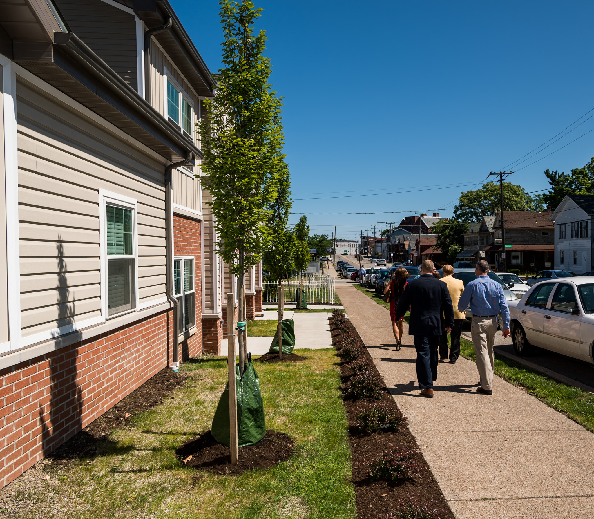 people walking down the sidewalk in front of a house